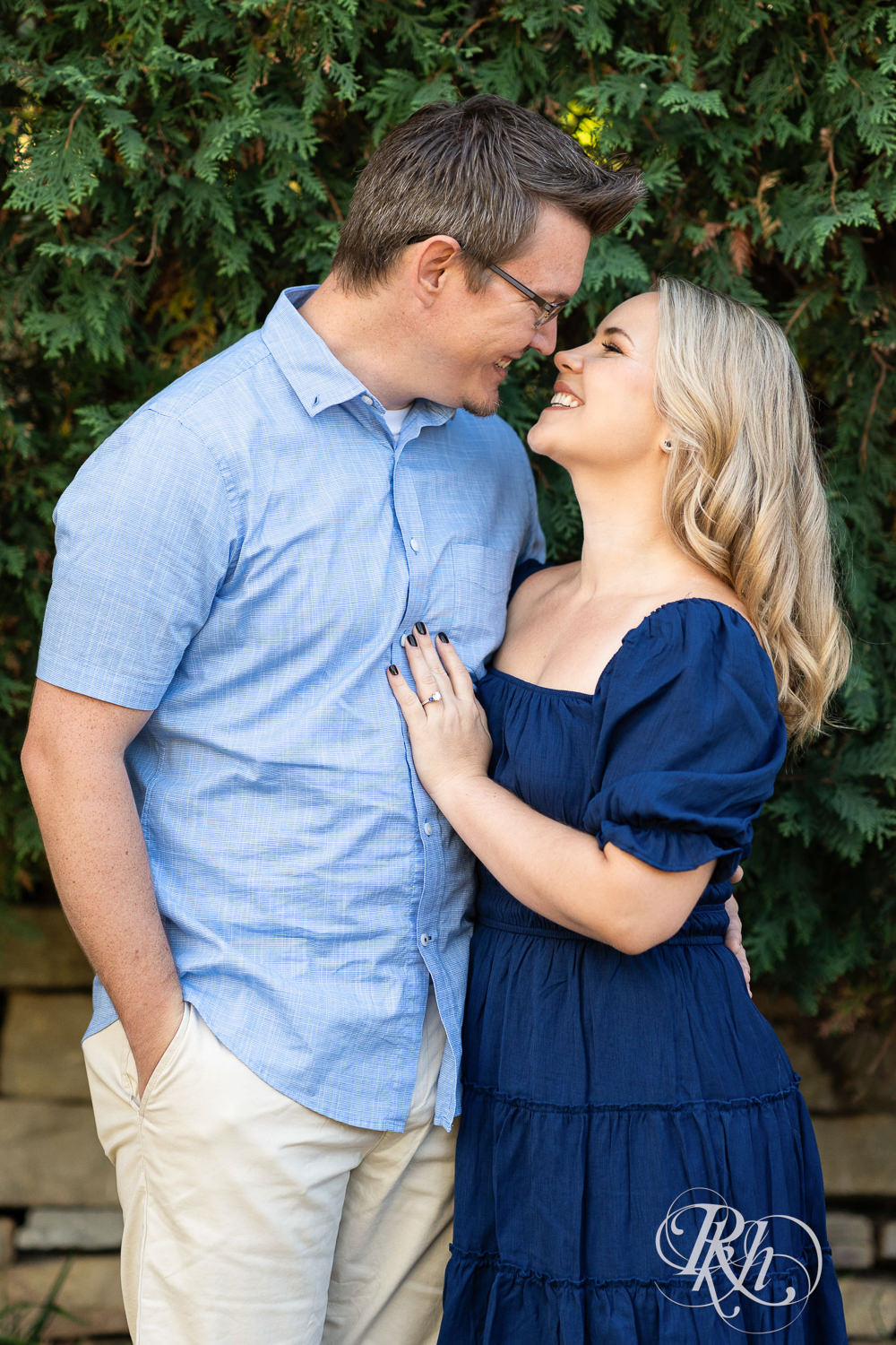 Man and woman in blue dress smile during morning engagement photography at Centennial Lakes Park in Edina, Minnesota.