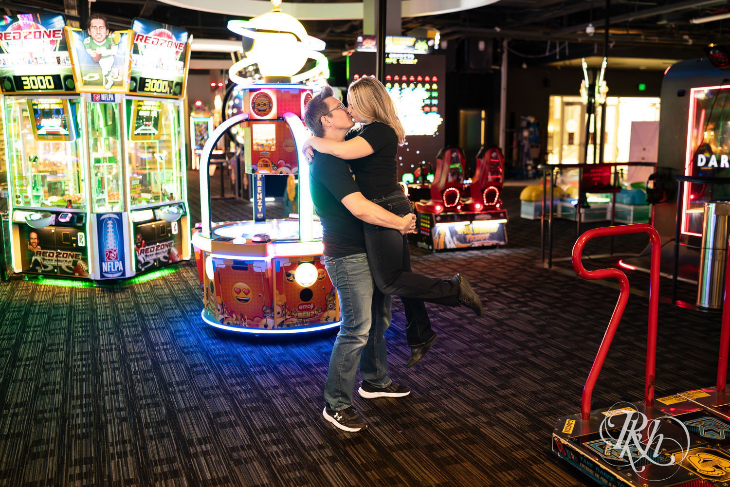 Man and woman in Zelda shirts kiss in Dave and Busters. 