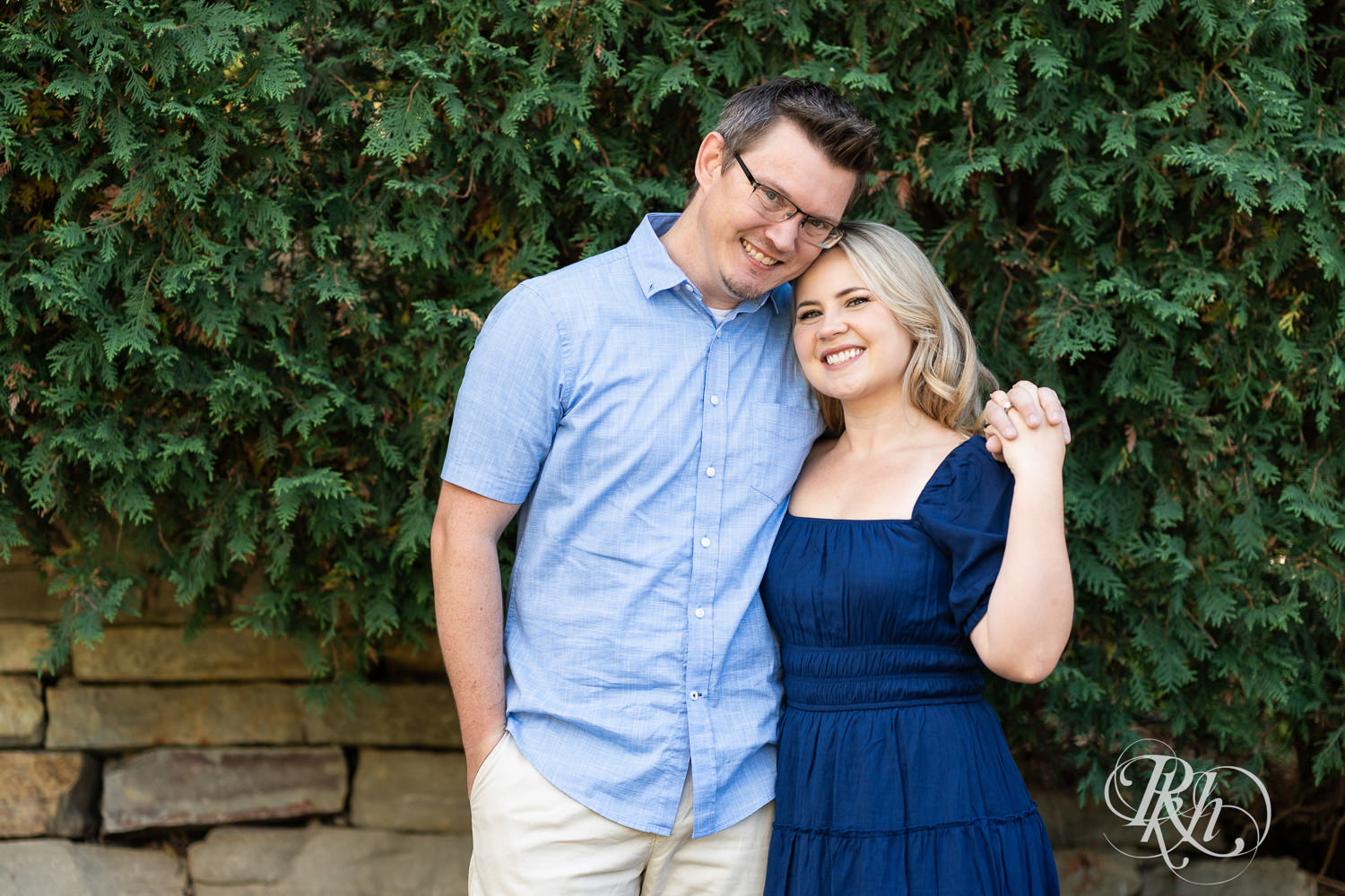 Man and woman in blue dress smile during morning engagement photography at Centennial Lakes Park in Edina, Minnesota.