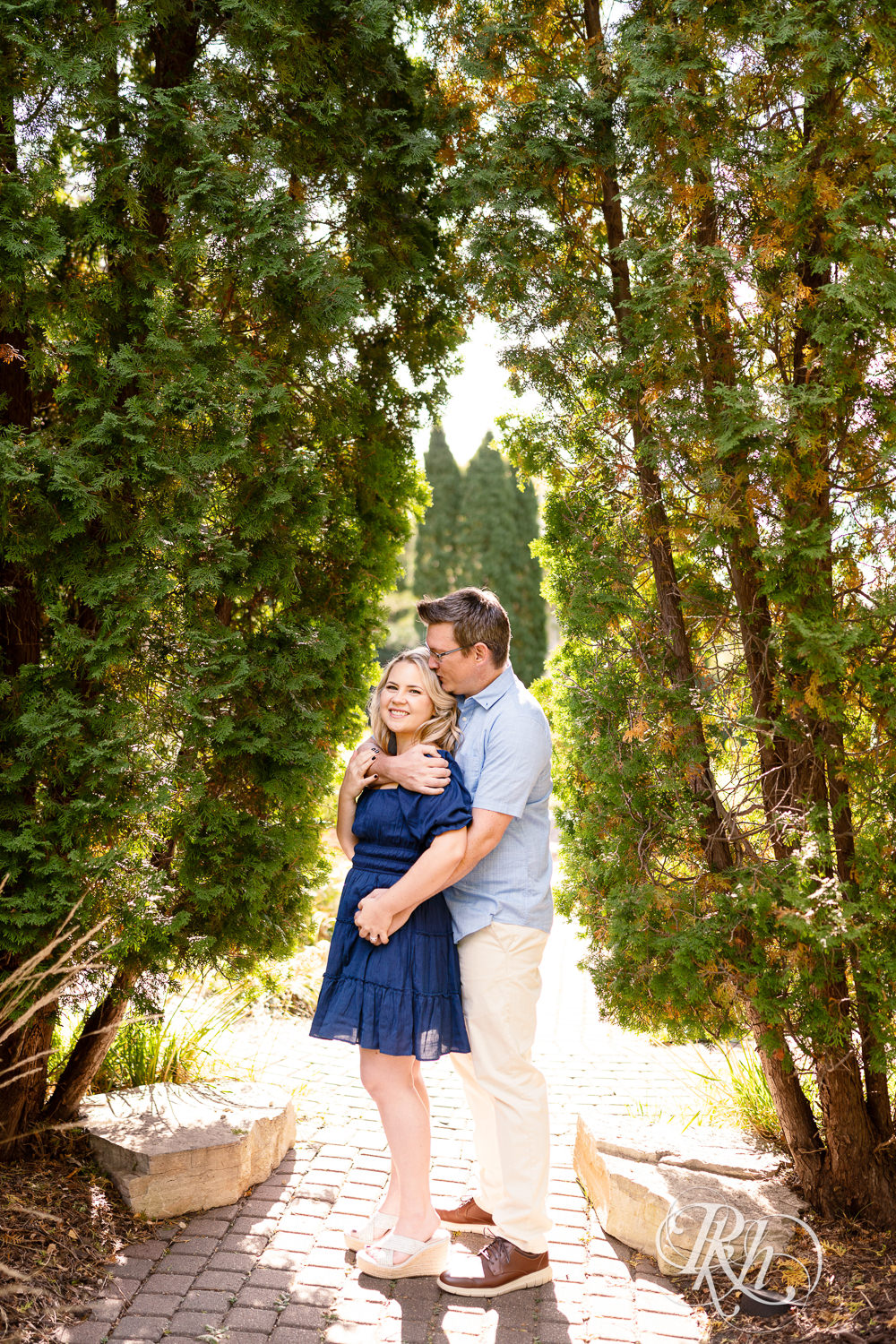 Man and woman in blue dress smile during morning engagement photography at Centennial Lakes Park in Edina, Minnesota.