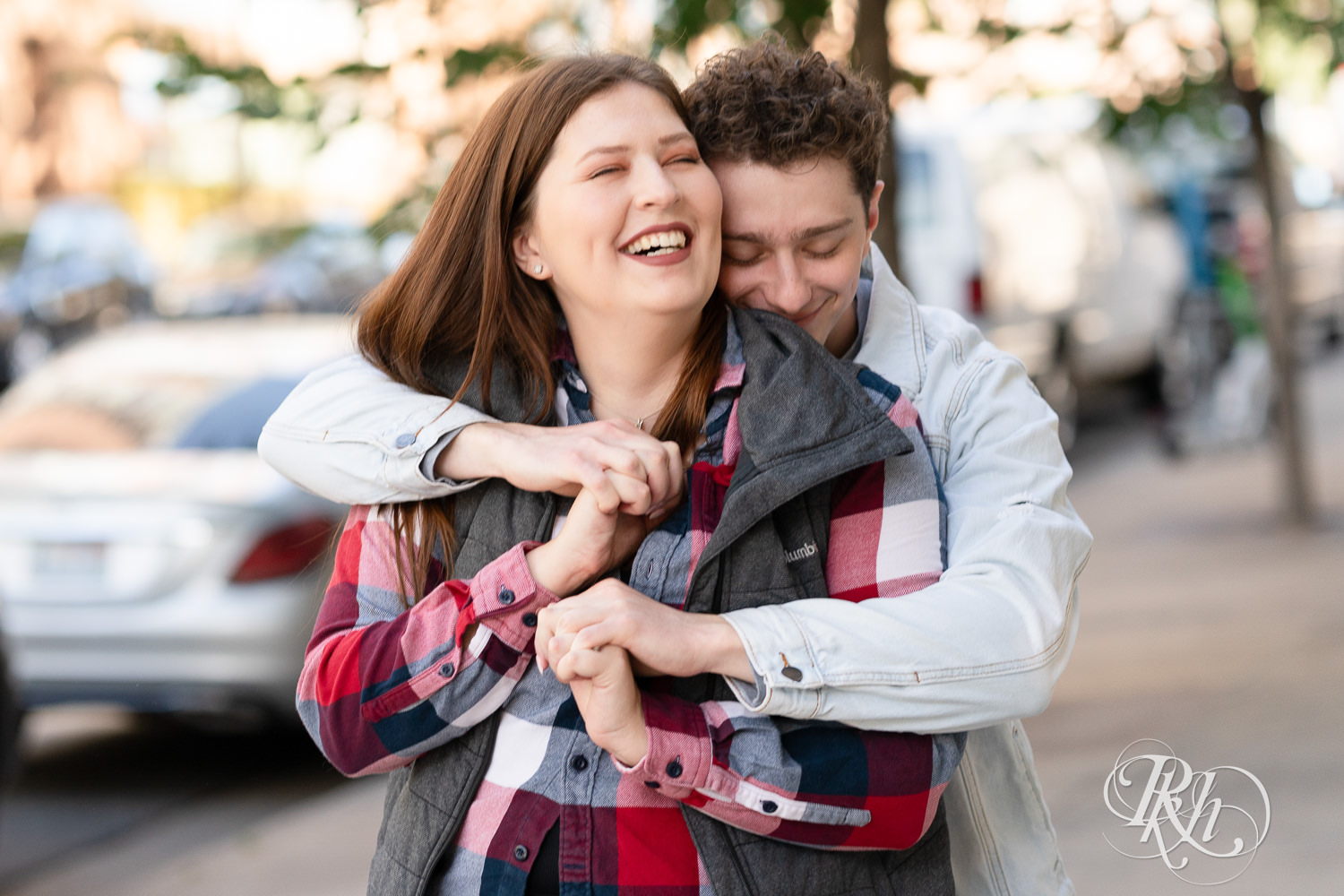 Man and woman in flannel laugh during city engagement photography in Minneapolis, Minnesota.