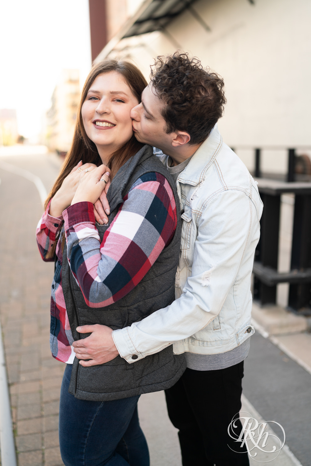 Man and woman in flannel kiss during city engagement photography in Minneapolis, Minnesota.