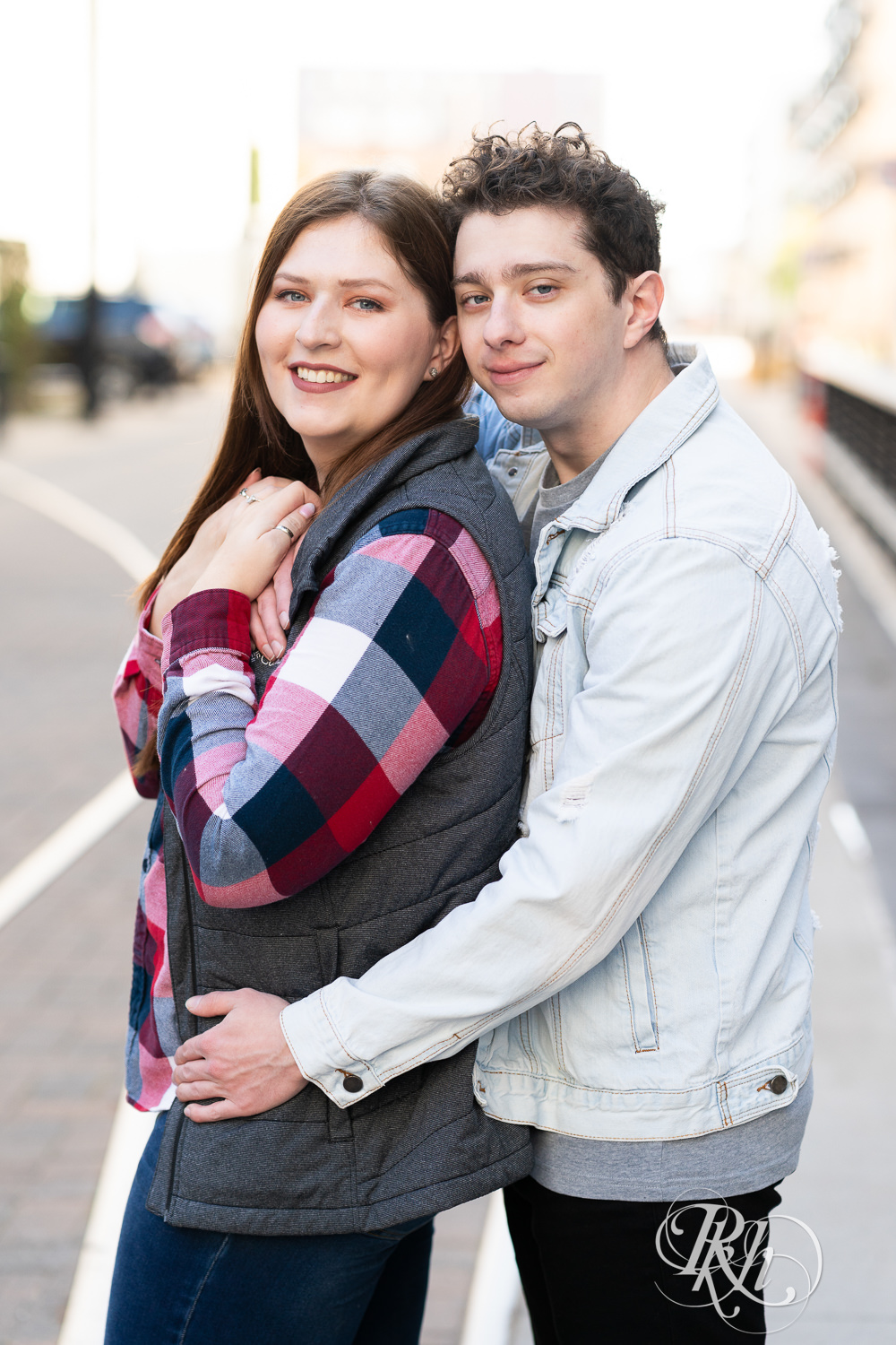Man and woman in flannel smile during city engagement photography in Minneapolis, Minnesota.