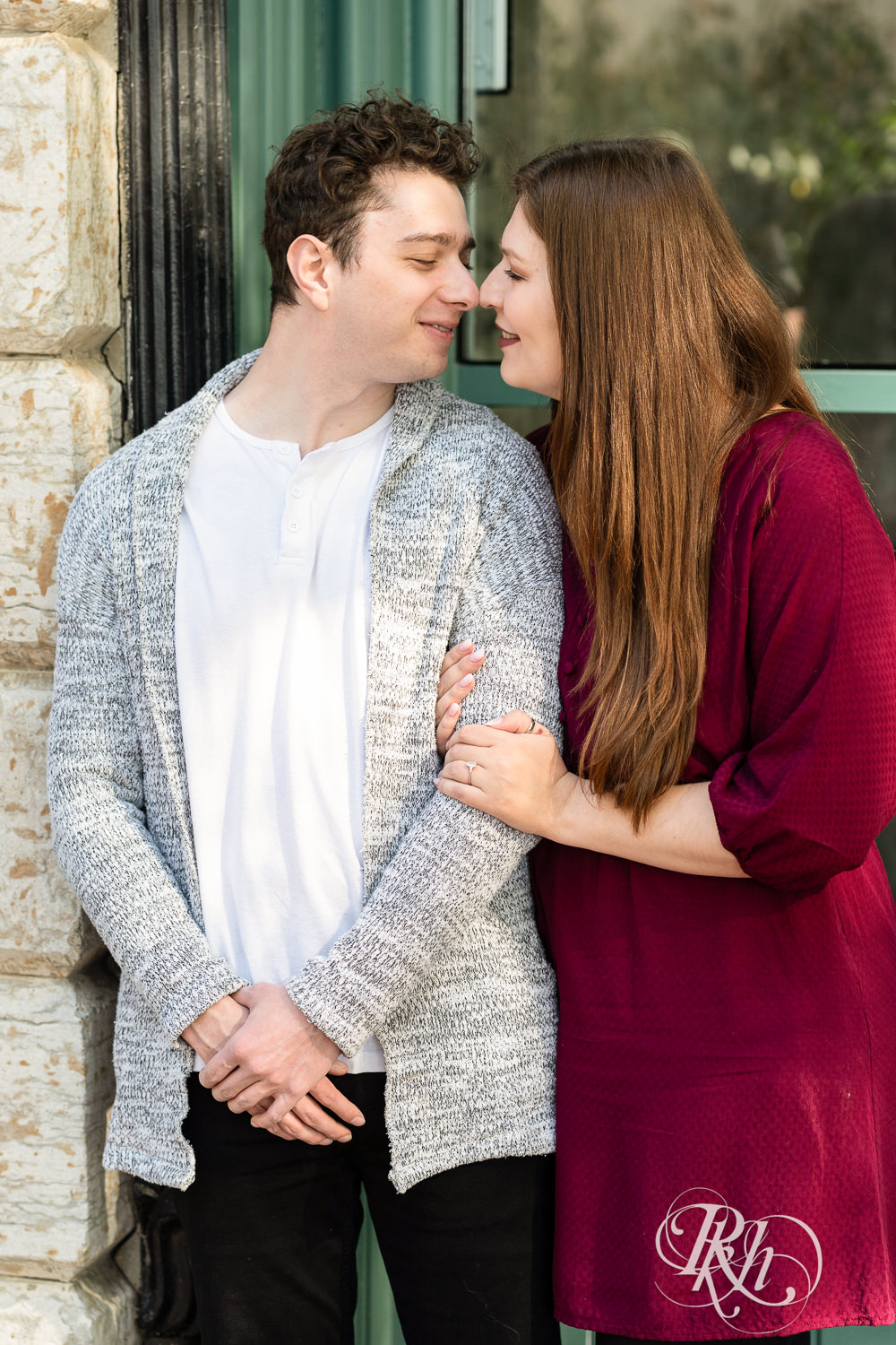 Man and woman in red dress smile during their city engagement photography in Minneapolis, Minnesota.