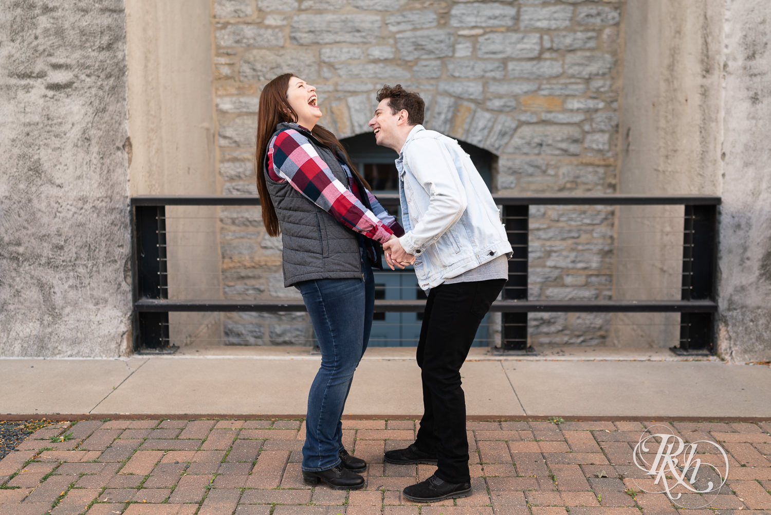 Man and woman in flannel laugh while holding hands on the street in Minneapolis, Minnesota.