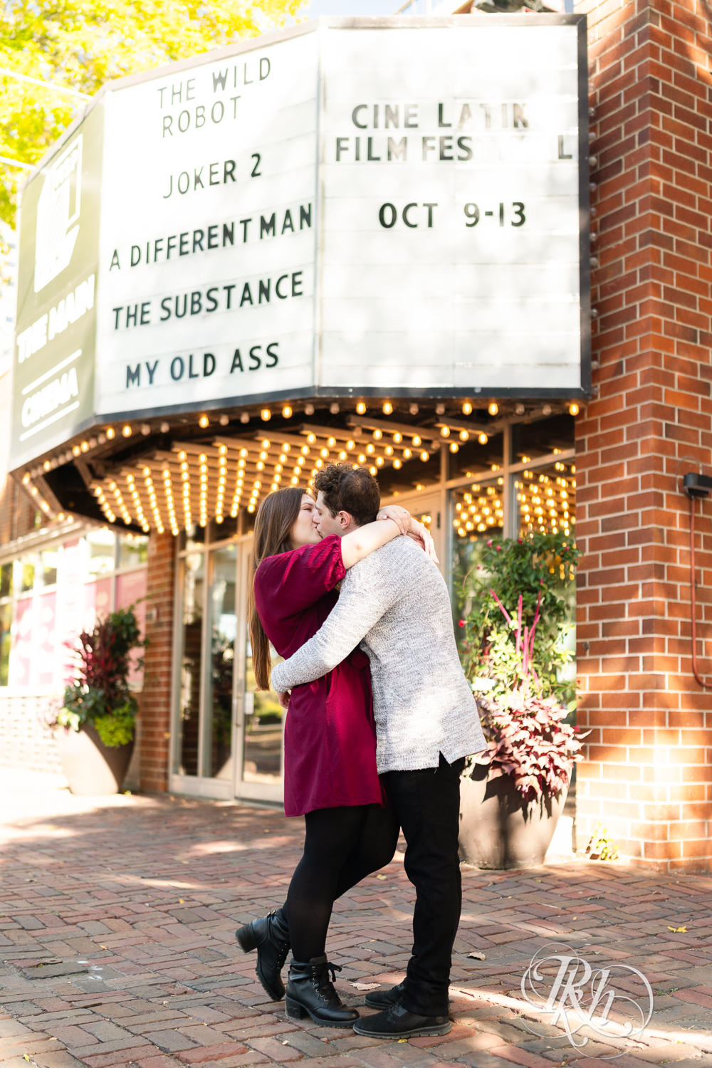 Man and woman in red dress kiss under theater marquee in Minneapolis, Minnesota.