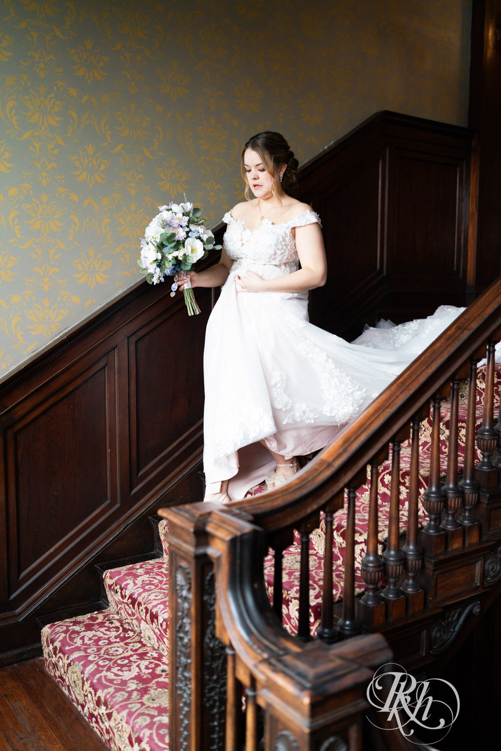 Bride walks down mansion stairs on wedding day at the Semple Mansion in Minneapolis, Minnesota.