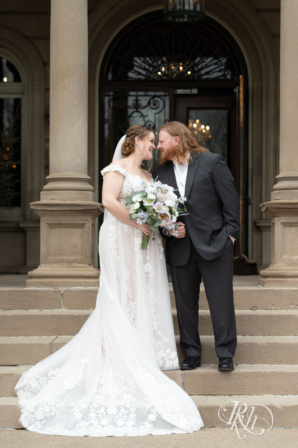 Bride and groom smile standing on the mansion stairs on their wedding day at the Semple Mansion in Minneapolis, Minnesota.