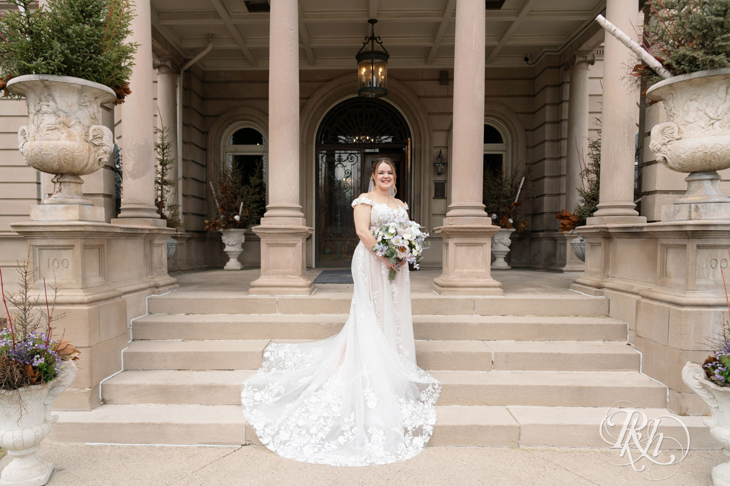 Bride stands on mansion stairs on their wedding day at the Semple Mansion in Minneapolis, Minnesota.