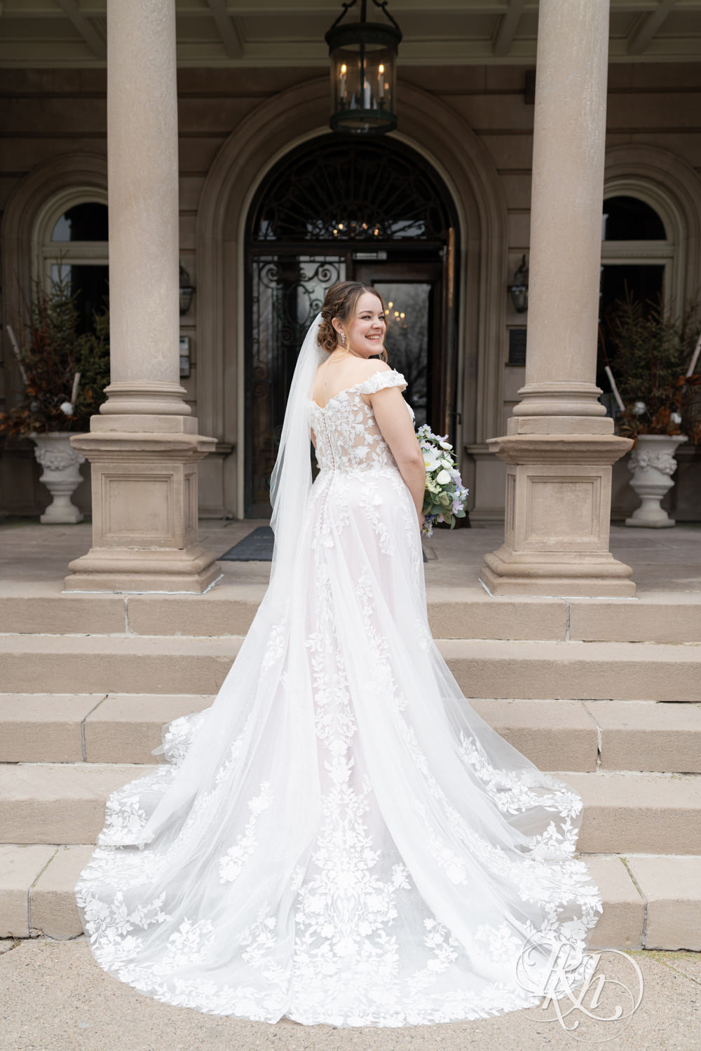 Bride stands on mansion stairs on their wedding day at the Semple Mansion in Minneapolis, Minnesota.