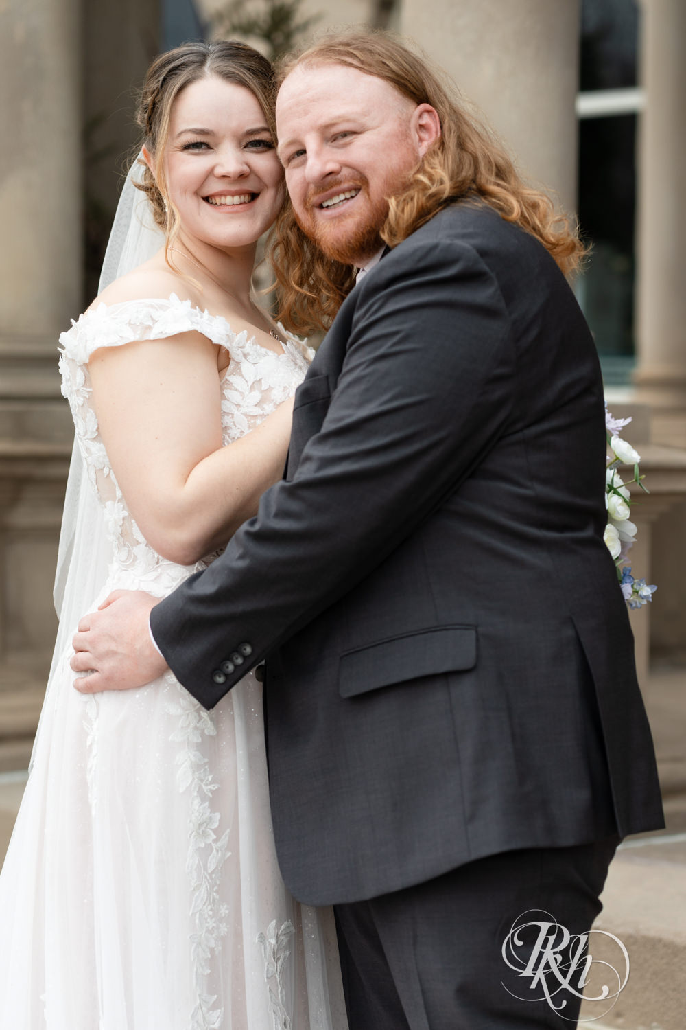 Bride and groom smile standing on the mansion stairs on their wedding day at the Semple Mansion in Minneapolis, Minnesota.