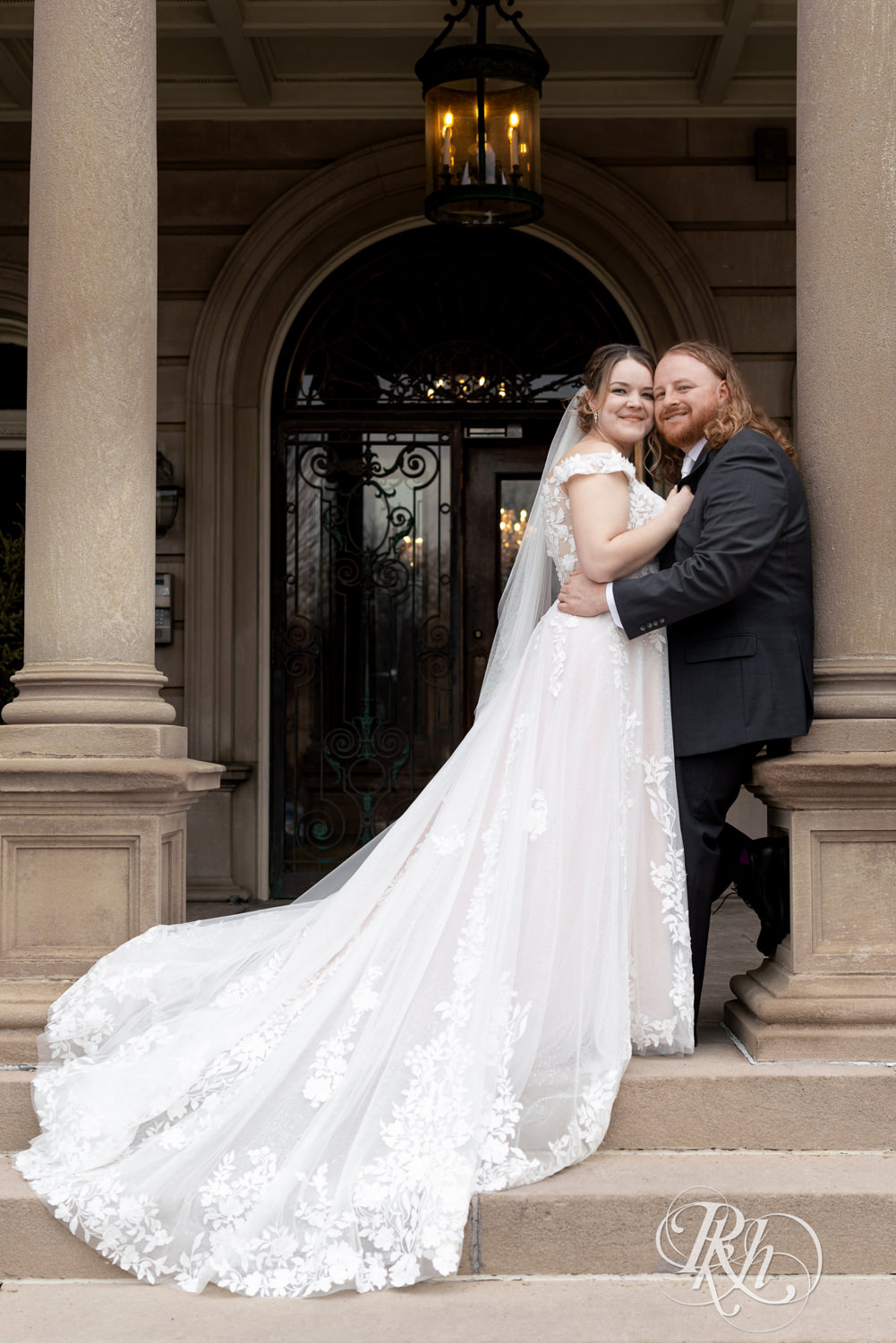 Bride and groom smile on the mansion stairs on their wedding day at the Semple Mansion in Minneapolis, Minnesota.