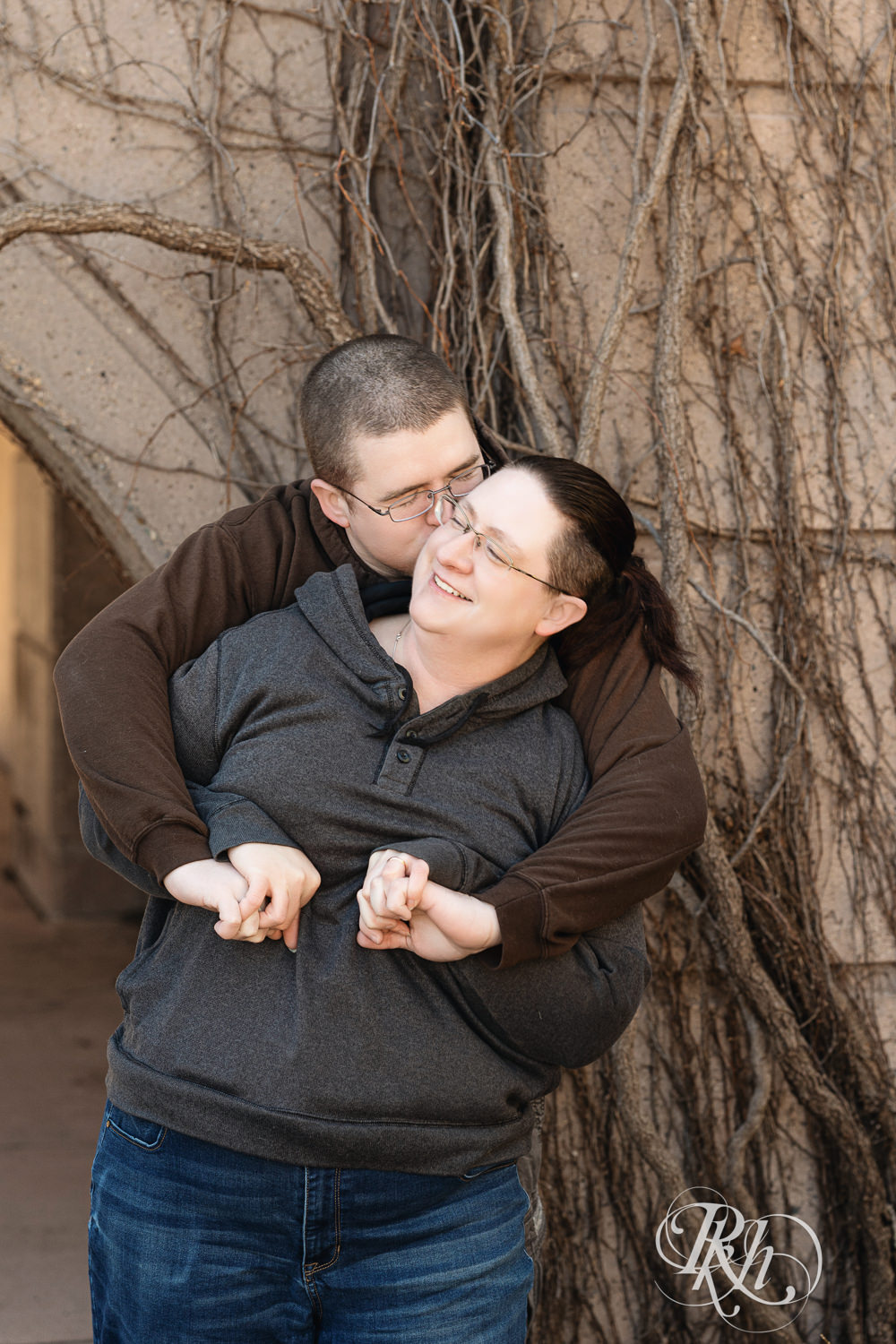 Man and woman in sweatshirts snuggle and laugh at Centennial Lakes Park in Edina, Minnesota.