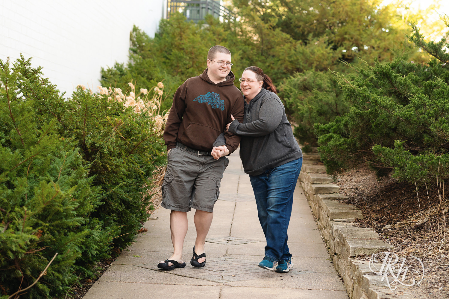 Man and woman in sweatshirts laugh while walking down path at Centennial Lakes Park in Edina, Minnesota.
