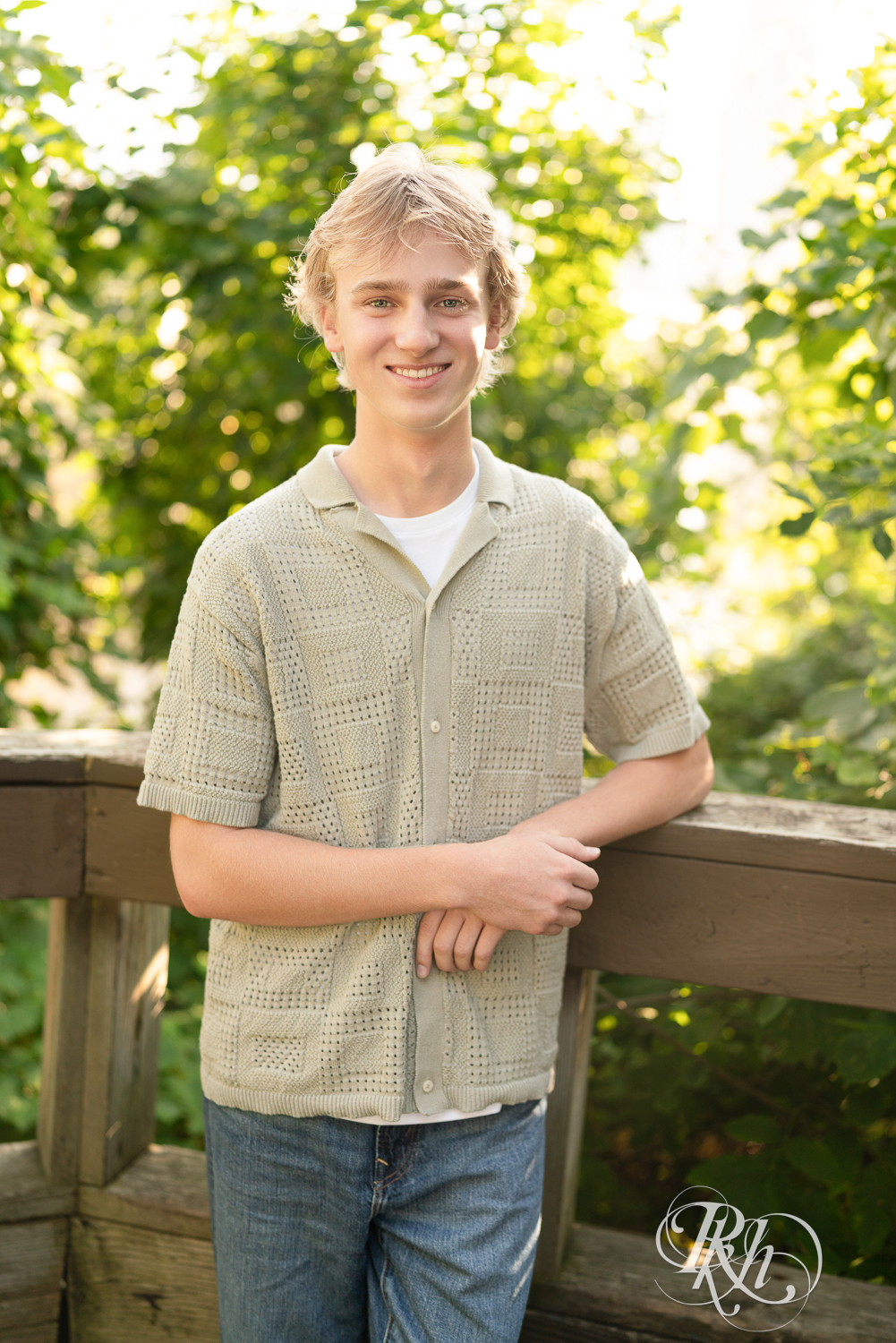 Blond senior boy smiles during senior photography at sunset in Minneapolis, Minnesota.