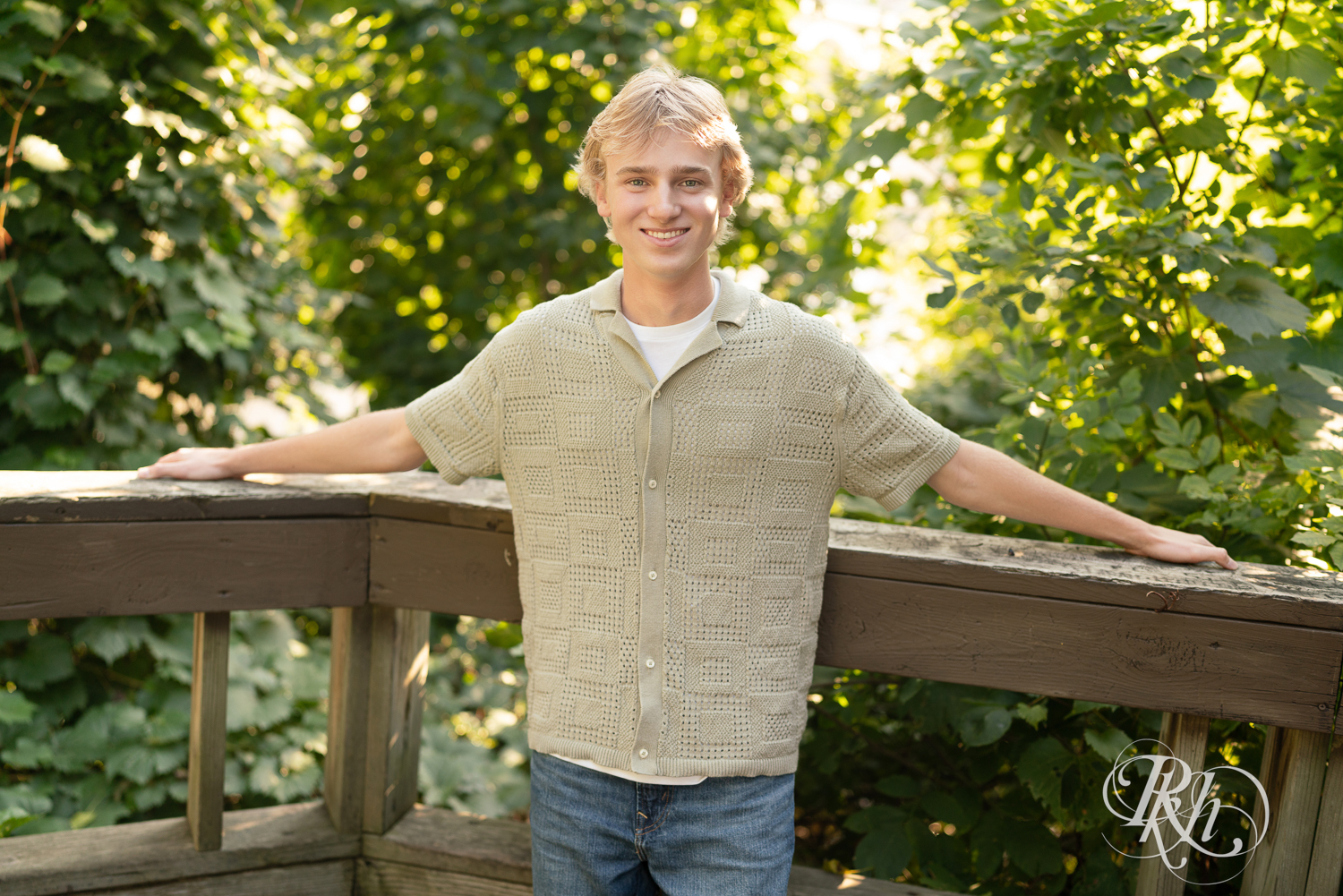 Blond senior boy smiles during senior photography at sunset in Minneapolis, Minnesota.