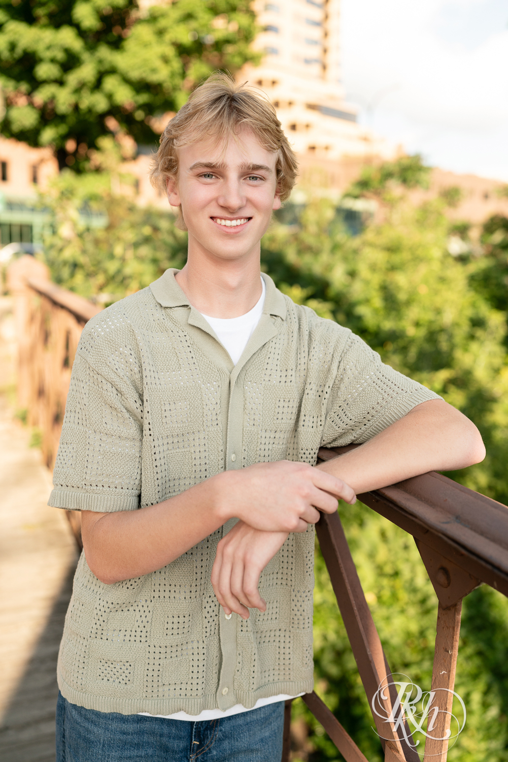 Blond senior boy smiles during senior photography at sunset in Minneapolis, Minnesota.