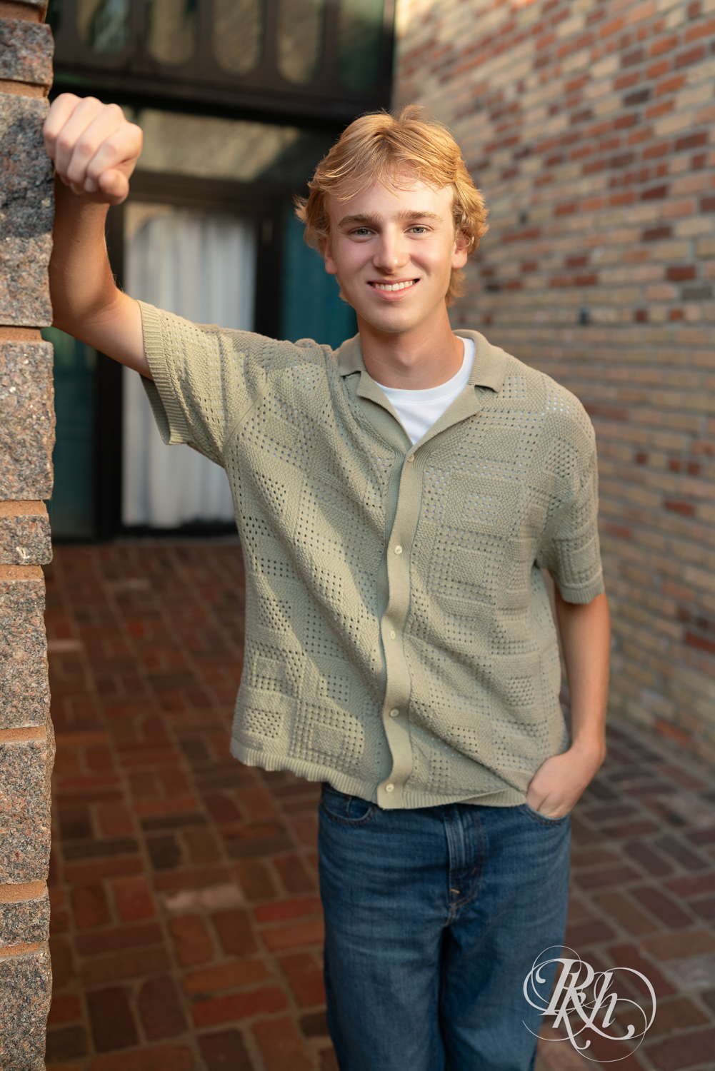 Blond senior boy smiles during senior photography at sunset in Minneapolis, Minnesota.