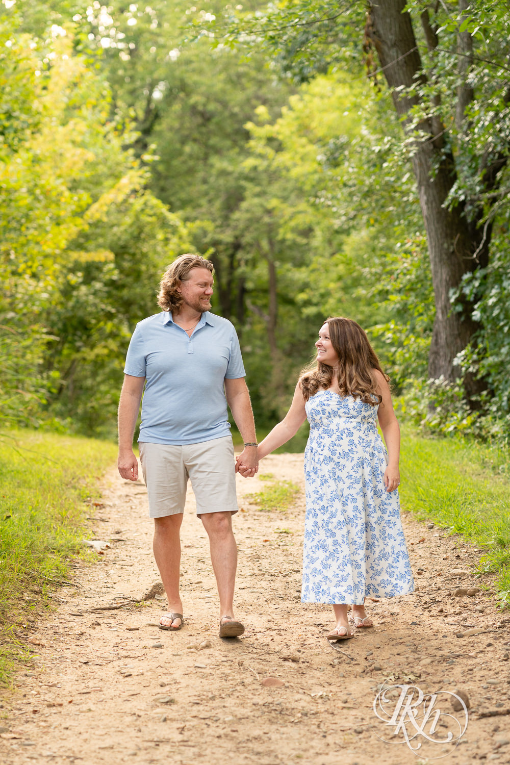 Man in blue shirt and khaki shorts and woman in blue and white dress walk down a trail in Eagan, Minnesota.