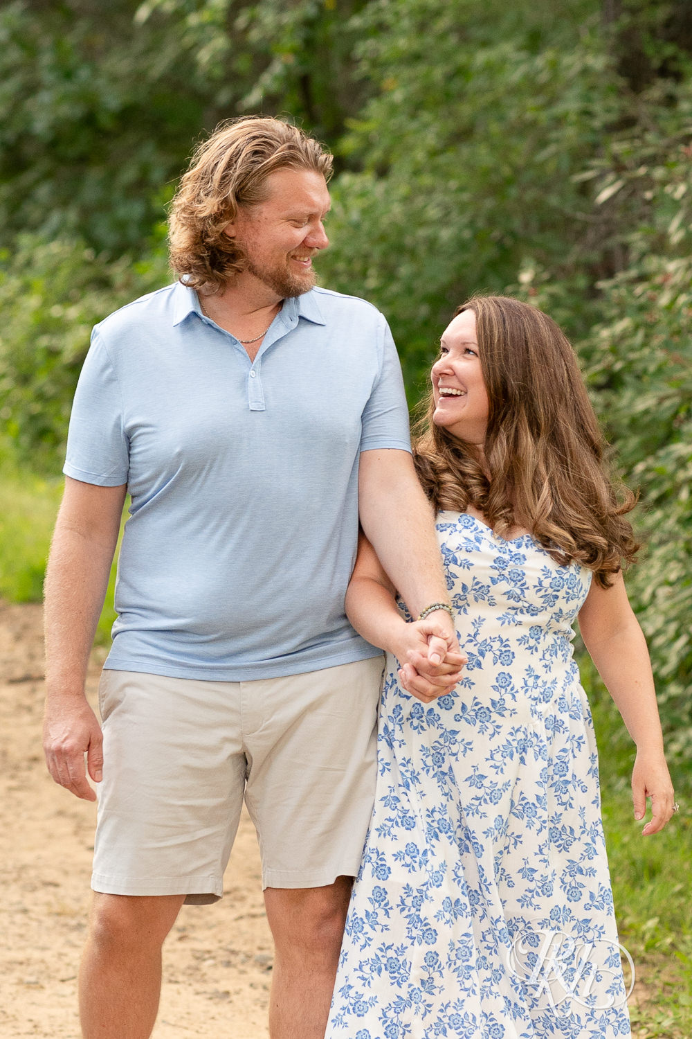 Man in blue shirt and khaki shorts and woman in blue and white dress walk down a trail in Eagan, Minnesota.