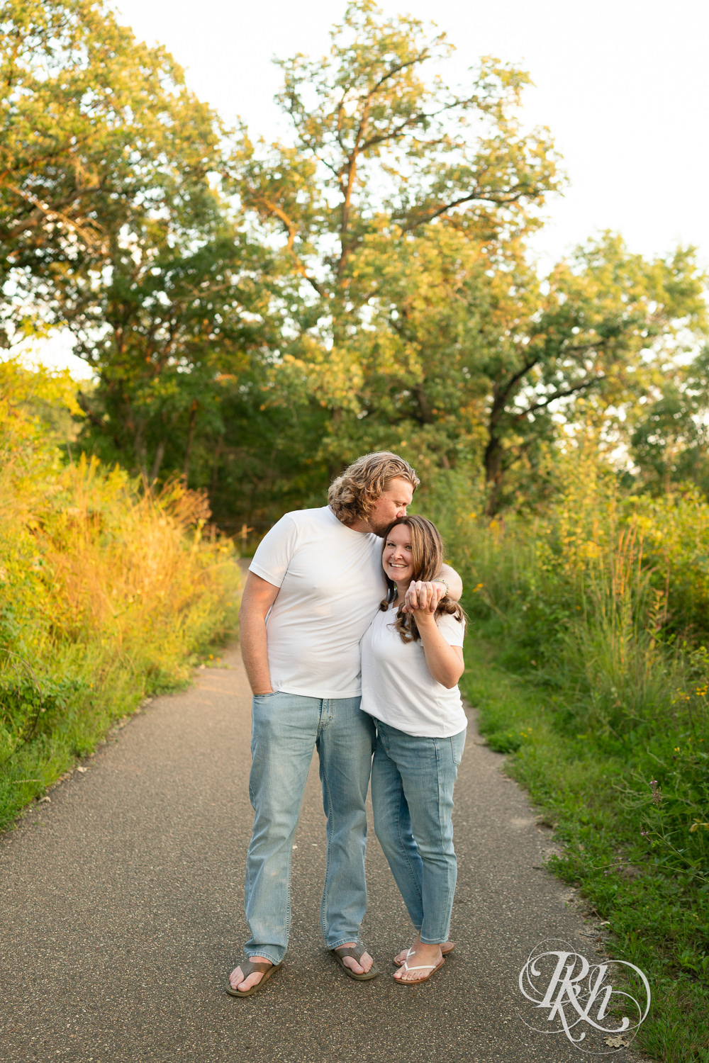 Man and woman dressed in white t-shirts and jeans walk down a path at sunset in Eagan, Minnesota.