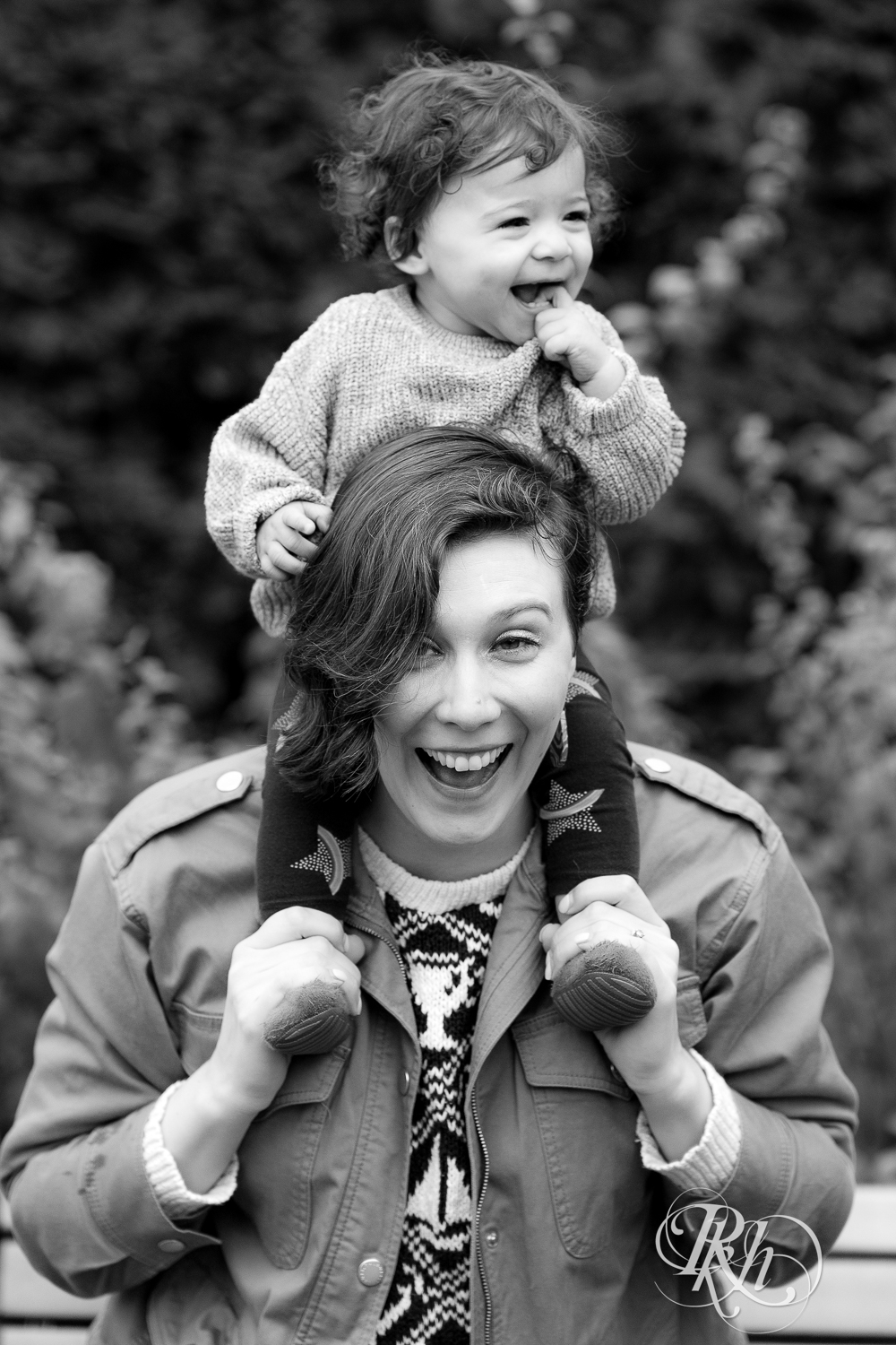 Little girl laughs while sitting on mom's shoulders at Como Park in Saint Paul, Minnesota.
