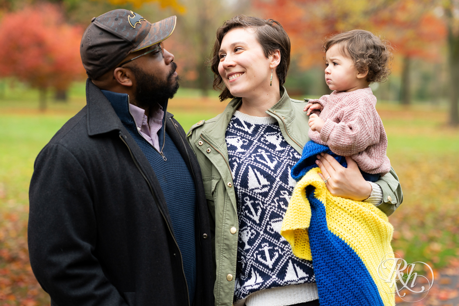 Mom smiles at dad while holding their daughter at Como Park in Saint Paul, Minnesota.