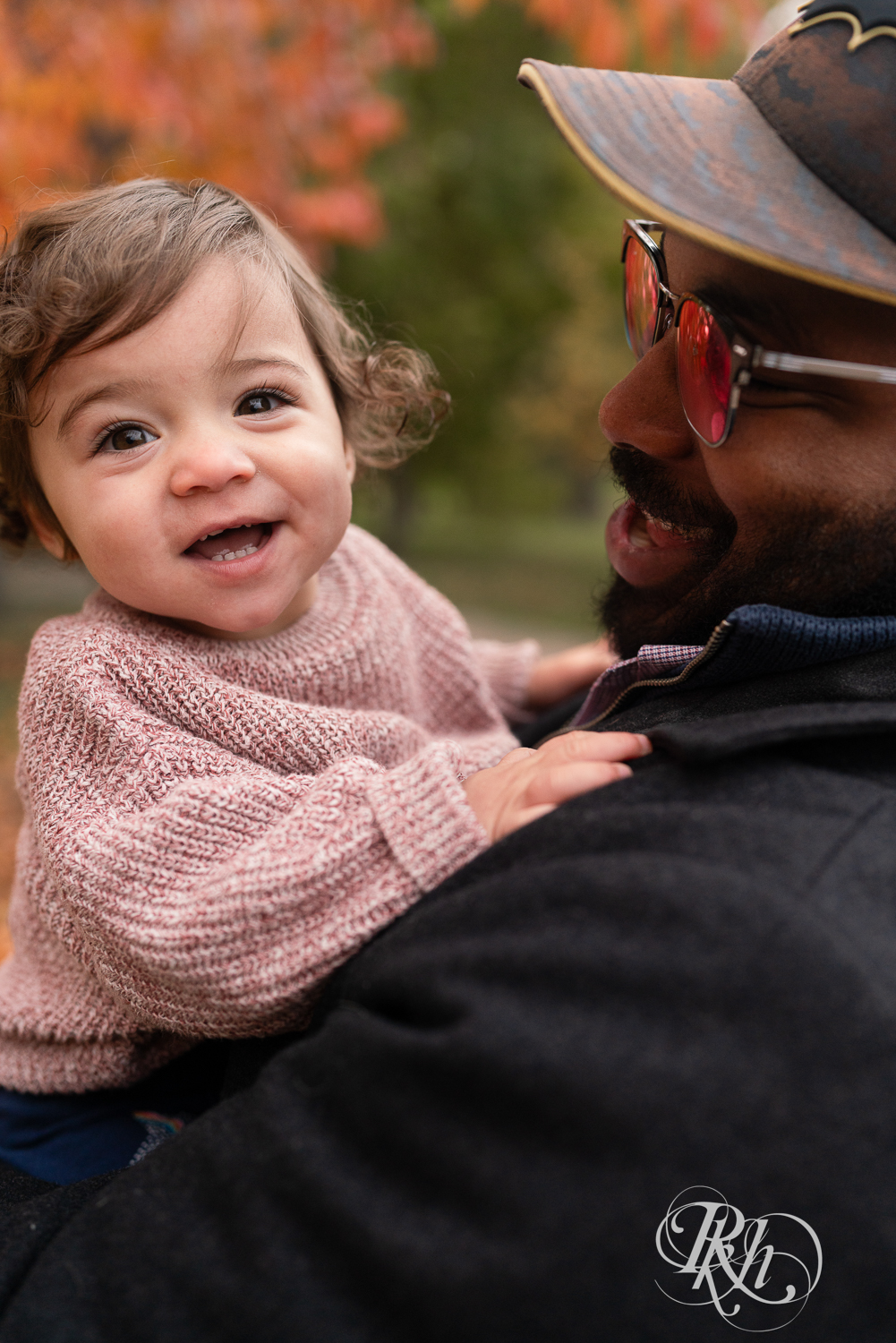 Little girl laughs while her dad holds her during a family photography session at Como Park in Saint Paul, Minnesota.