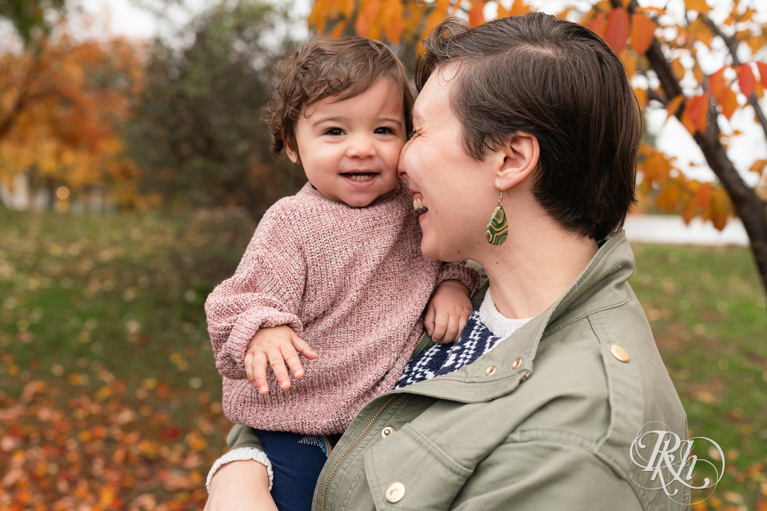 Little girl laughs against mom's face  during at Como Park in Saint Paul, Minnesota.