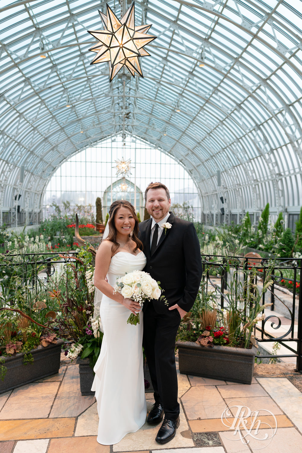 Asian bride and groom smile on wedding day at the Sunken Garden at the Como Zoo and Conservatory in Saint Paul, Minnesota.