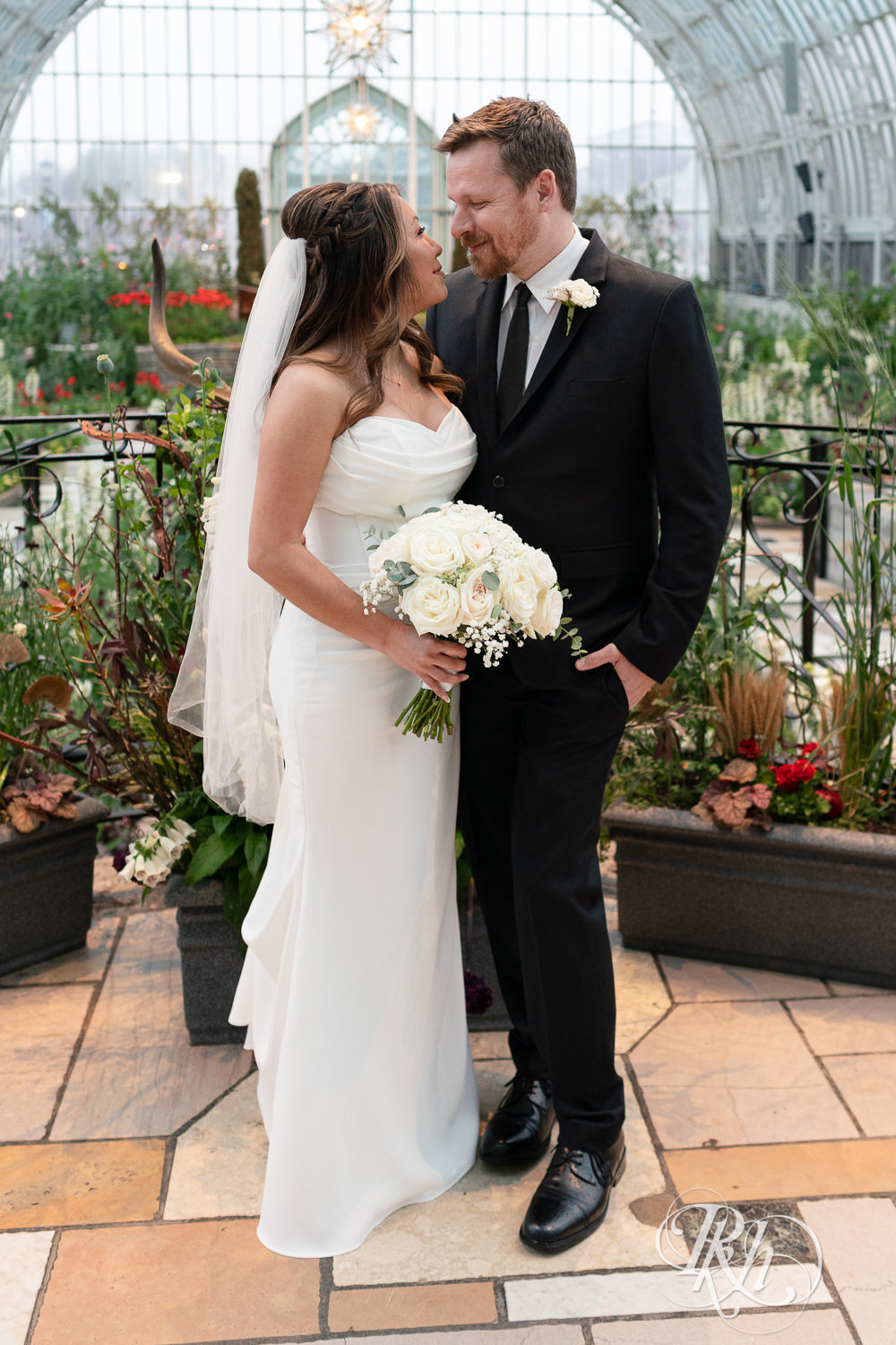 Asian bride and groom smile on wedding day at the Sunken Garden at the Como Zoo and Conservatory in Saint Paul, Minnesota.