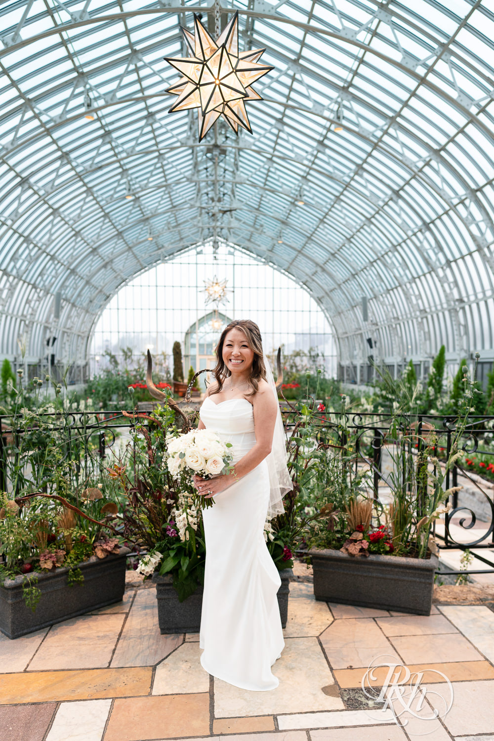 Asian bride smiles on wedding day at the Sunken Garden at the Como Zoo and Conservatory in Saint Paul, Minnesota.
