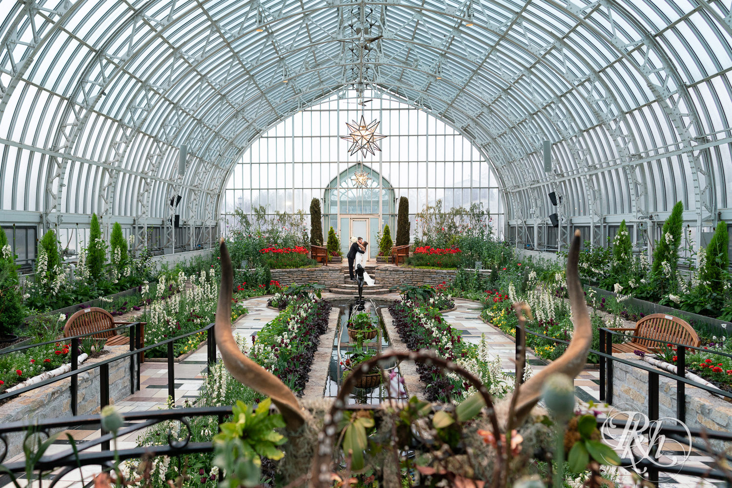 Asian bride and groom kiss on wedding day at the Sunken Garden at the Como Zoo and Conservatory in Saint Paul, Minnesota.