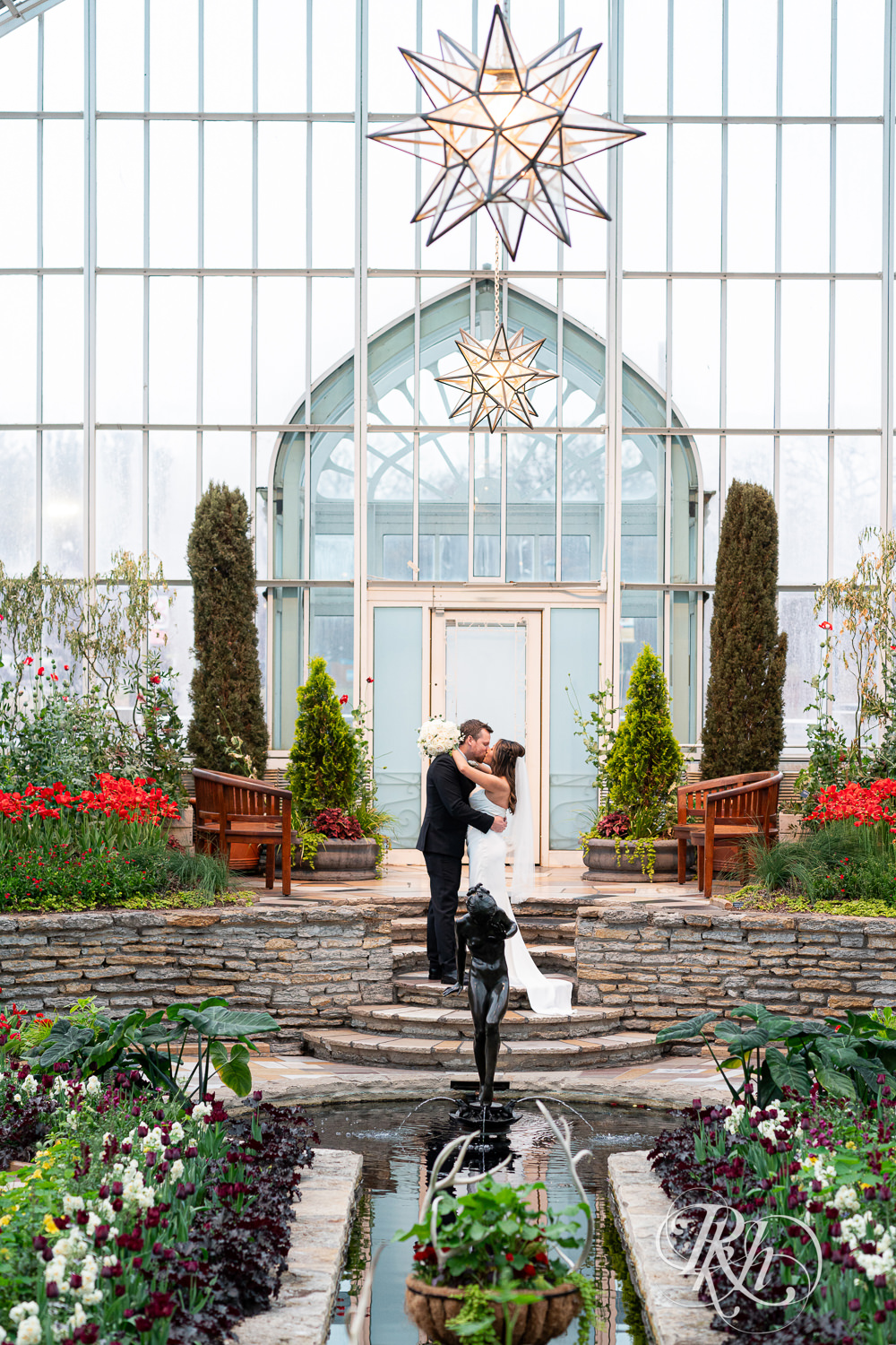 Asian bride and groom kiss on wedding day at the Sunken Garden at the Como Zoo and Conservatory in Saint Paul, Minnesota.