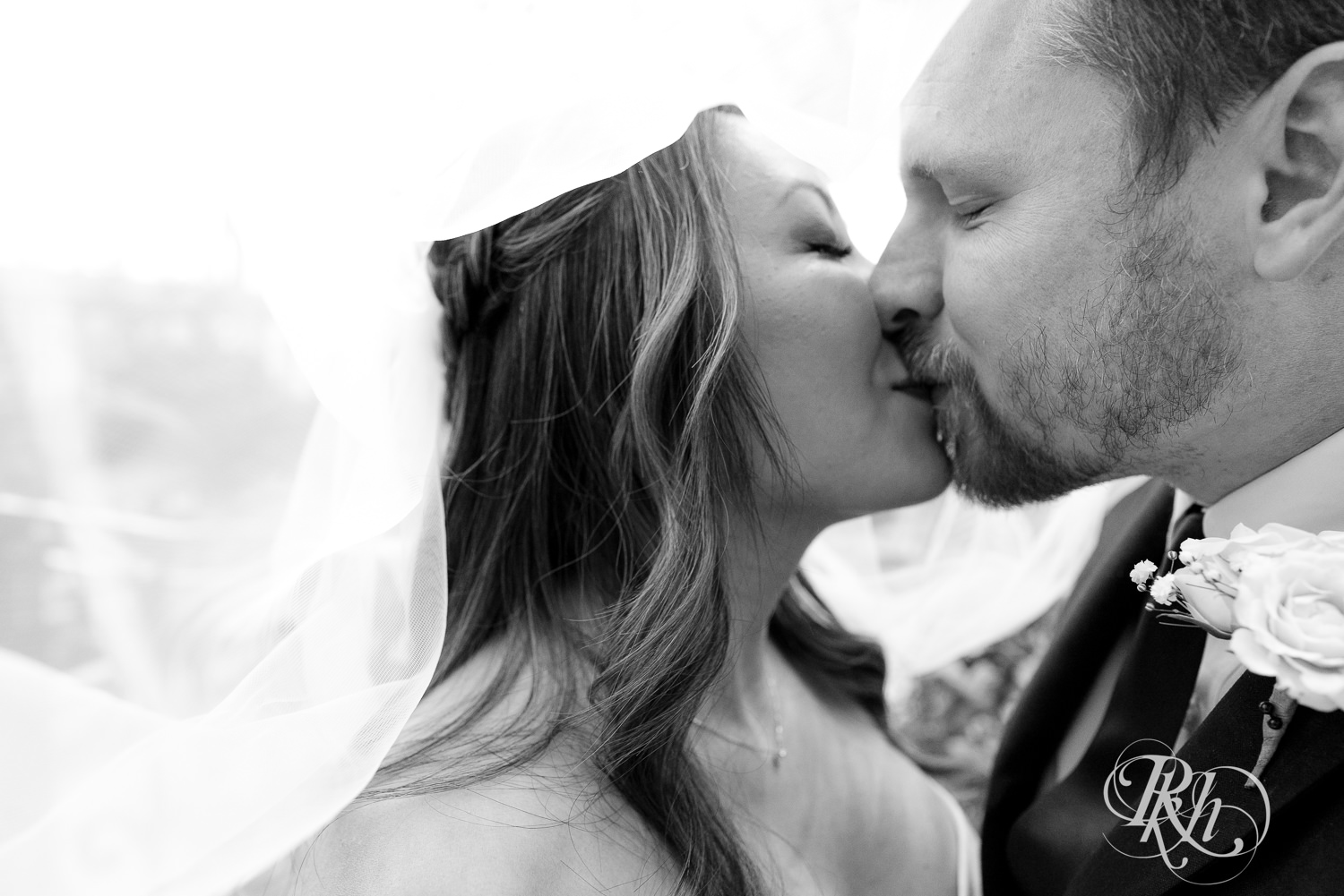 Asian bride and groom kiss under wedding veil at the Como Zoo and Conservatory in Saint Paul, Minnesota.