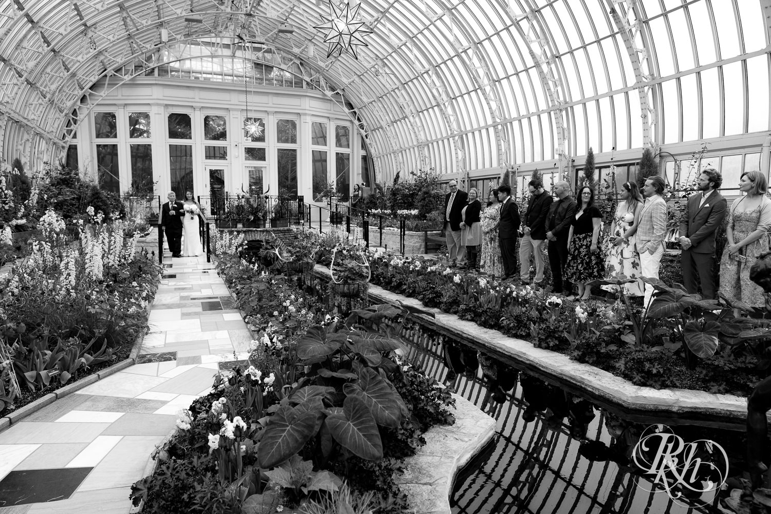 Asian bride walks down the aisle on wedding day at the Como Zoo and Conservatory in Saint Paul, Minnesota.