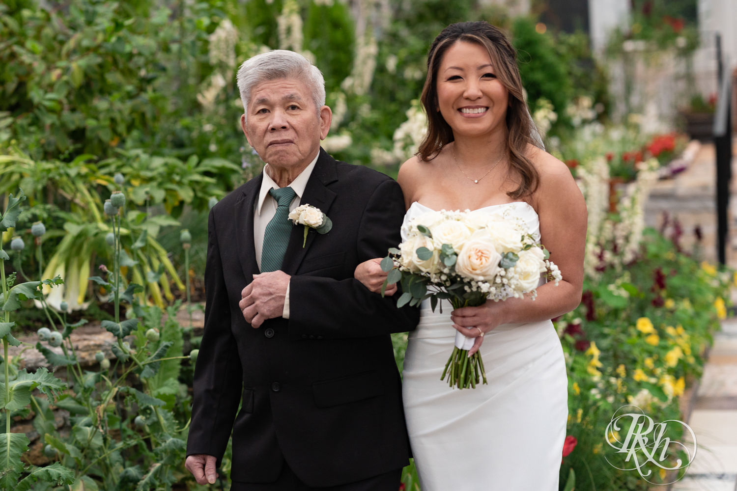 Asian bride walks down the aisle on wedding day at the Como Zoo and Conservatory in Saint Paul, Minnesota.