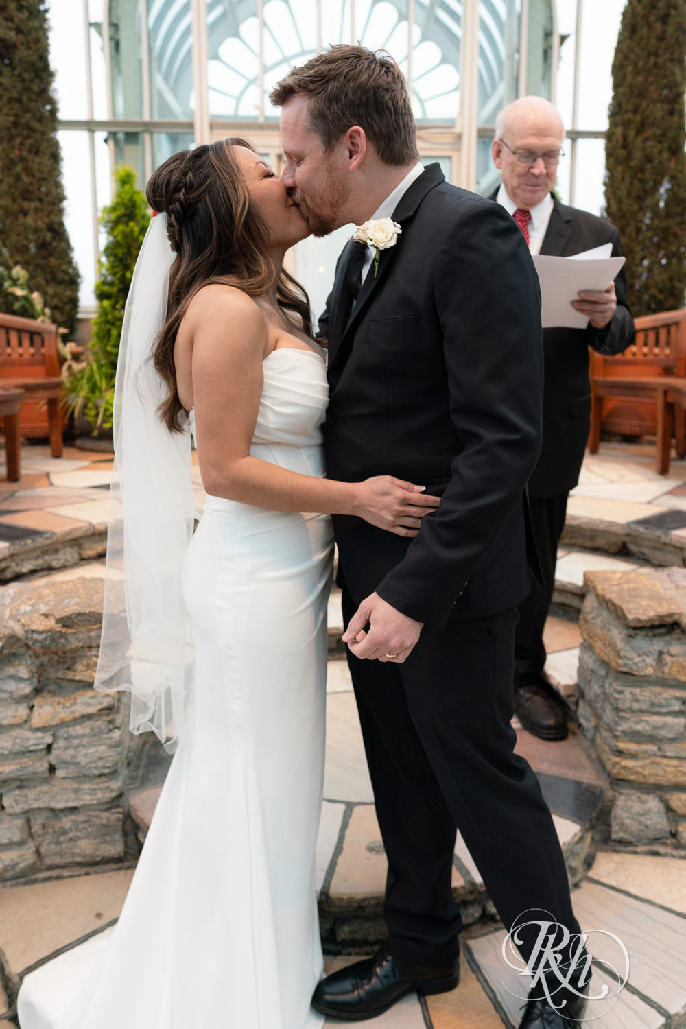 Bride and groom kiss during wedding ceremony in the Sunken Garden at the Como Zoo and Conservatory in Saint Paul, Minnesota.