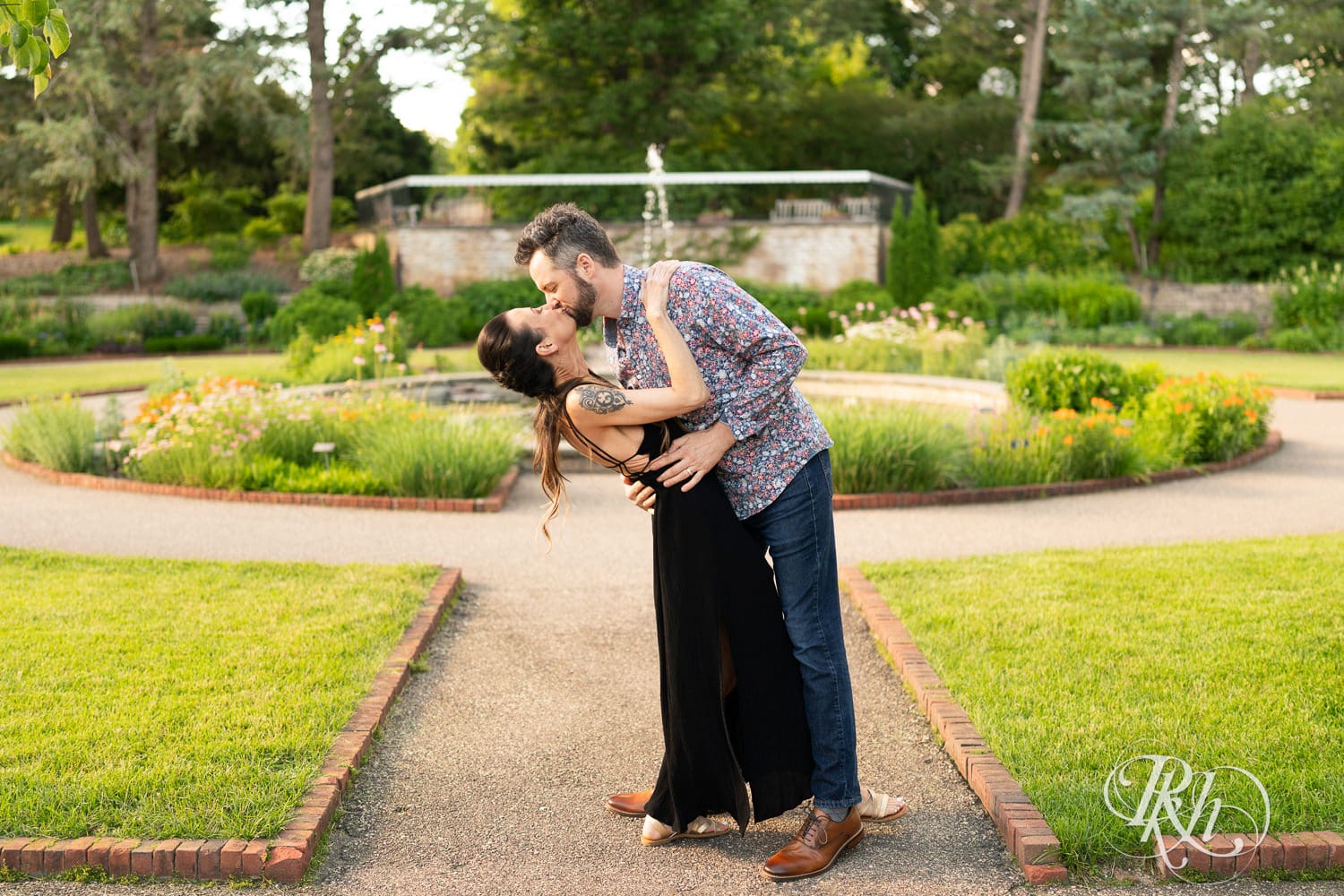 Man and woman kiss in front of the fountain at the Minnesota Landscape Arboretum in Chaska, Minnesota.