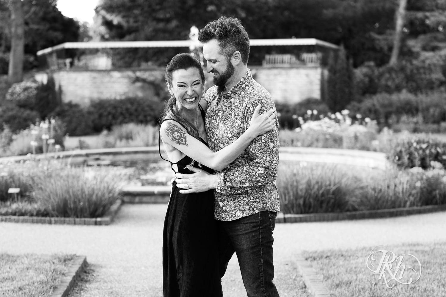 Man and woman laugh in front of the fountain at the Minnesota Landscape Arboretum in Chaska, Minnesota.