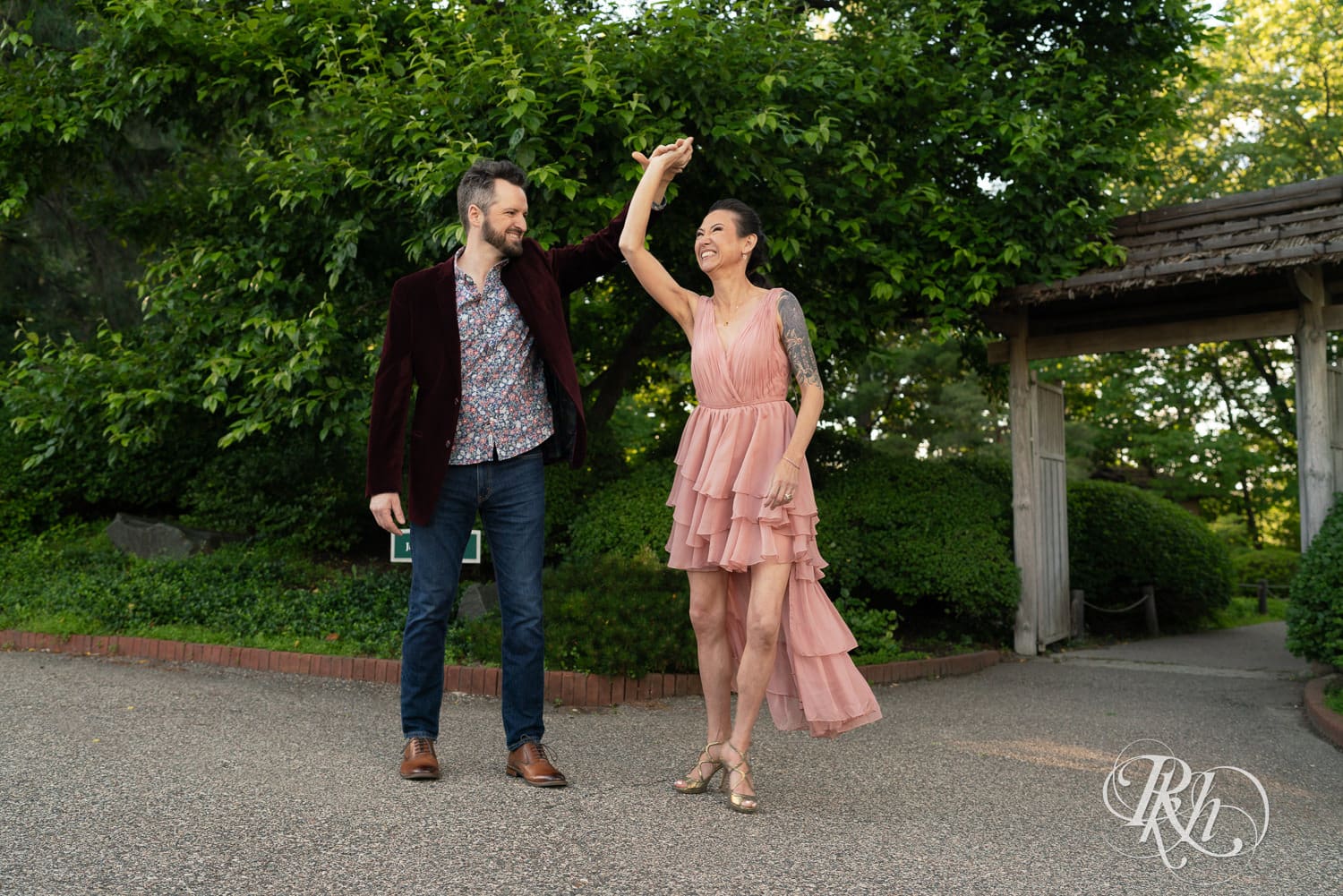 Man in red velvet jacket and woman in pink dress dance at the Minnesota Landscape Arboretum in Chaska, Minnesota.