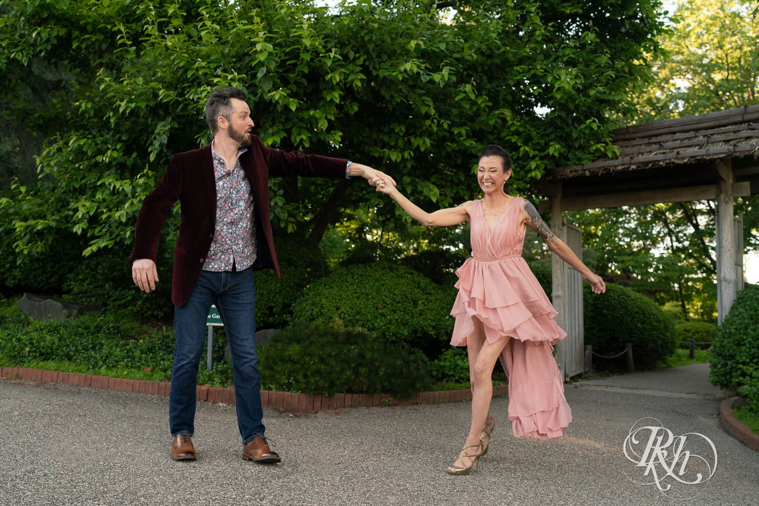Man in red velvet jacket and woman in pink dress dance at the Minnesota Landscape Arboretum in Chaska, Minnesota.