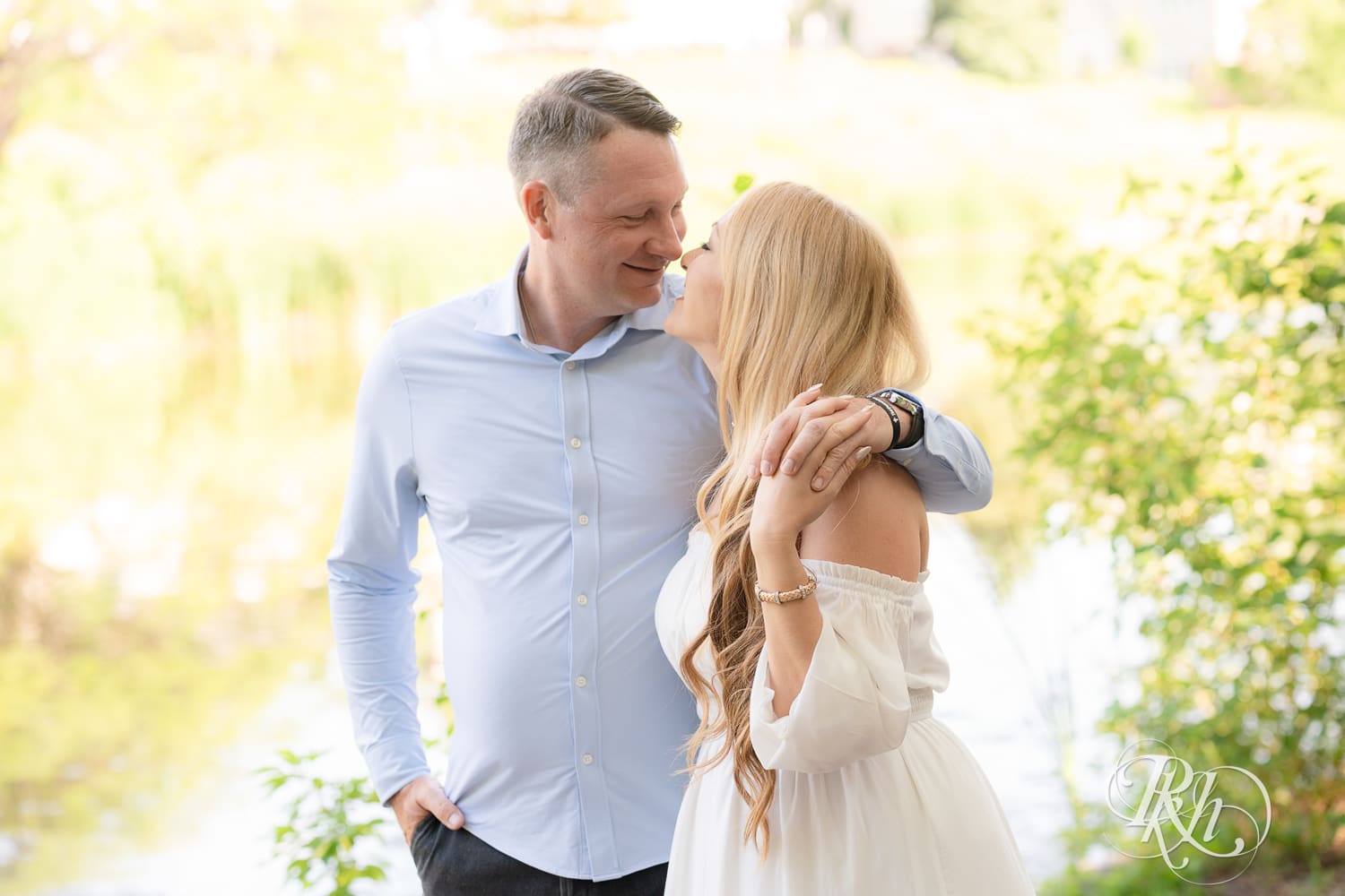 Man in jeans and blond woman in a white dress smile at Centennial Lake Park in Edina, Minnesota.
