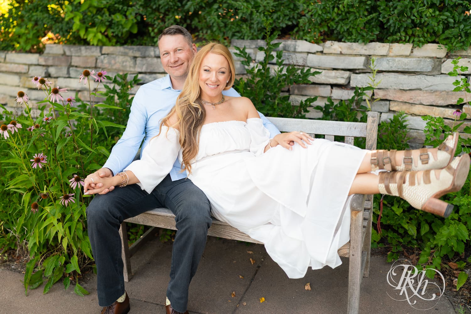Man in jeans and blond woman in a white dress sit on a bench at Centennial Lake Park in Edina, Minnesota.