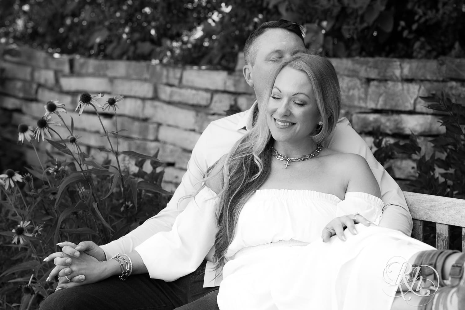 Man in jeans and blond woman in a white dress sit on a bench at Centennial Lake Park in Edina, Minnesota.