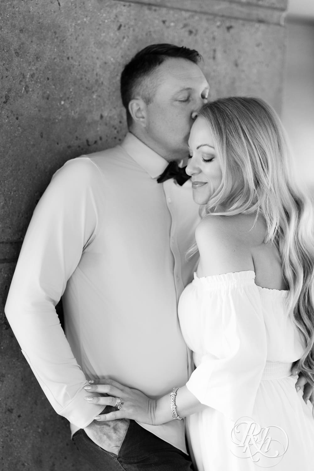 Man in jeans and blond woman in a white dress smile under a bridge at Centennial Lake Park in Edina, Minnesota.